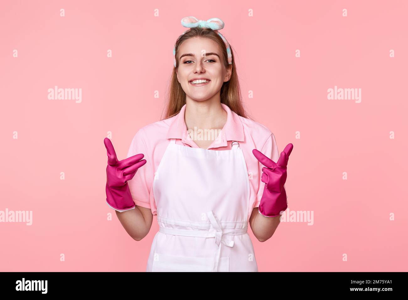 woman in rubber gloves and cleaner apron pointing fingers to camera Stock Photo