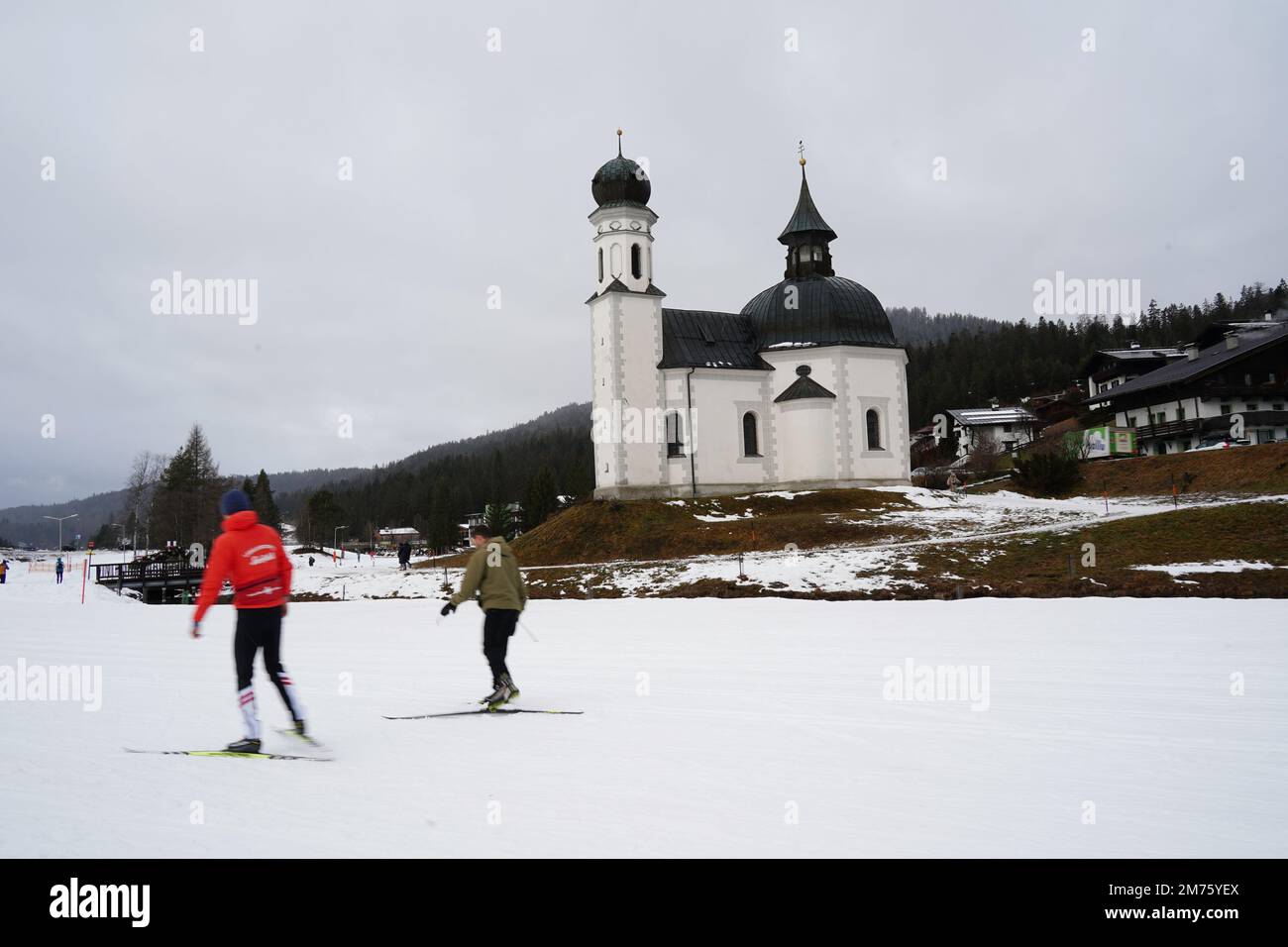Seefeld, Austria - December 2022: Crosscrountry skiers (in motion blur) skiing near the Seekirchl chapel (also known as Heiligkreuzkirche) in Seefeld Stock Photo