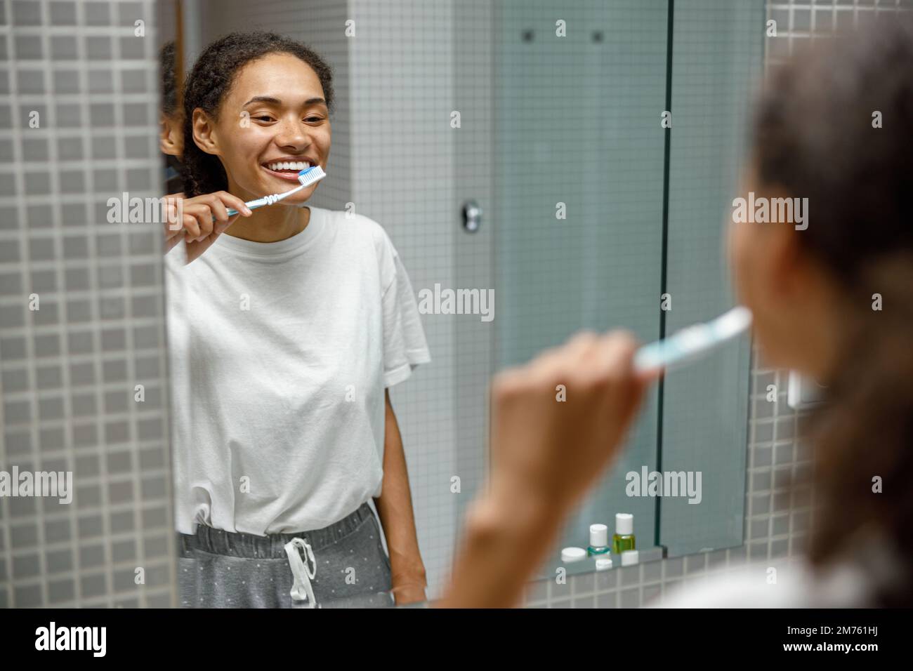 Beautiful woman brushing teeth in front of her bathroom mirror. Morning