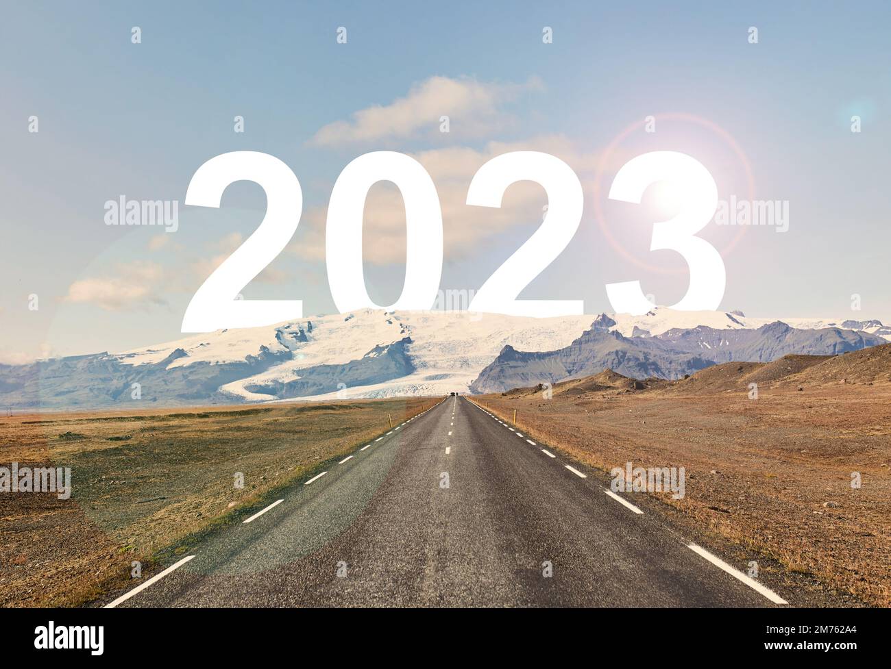 The word 2023 is written behind a glacier and an empty asphalt road Stock Photo
