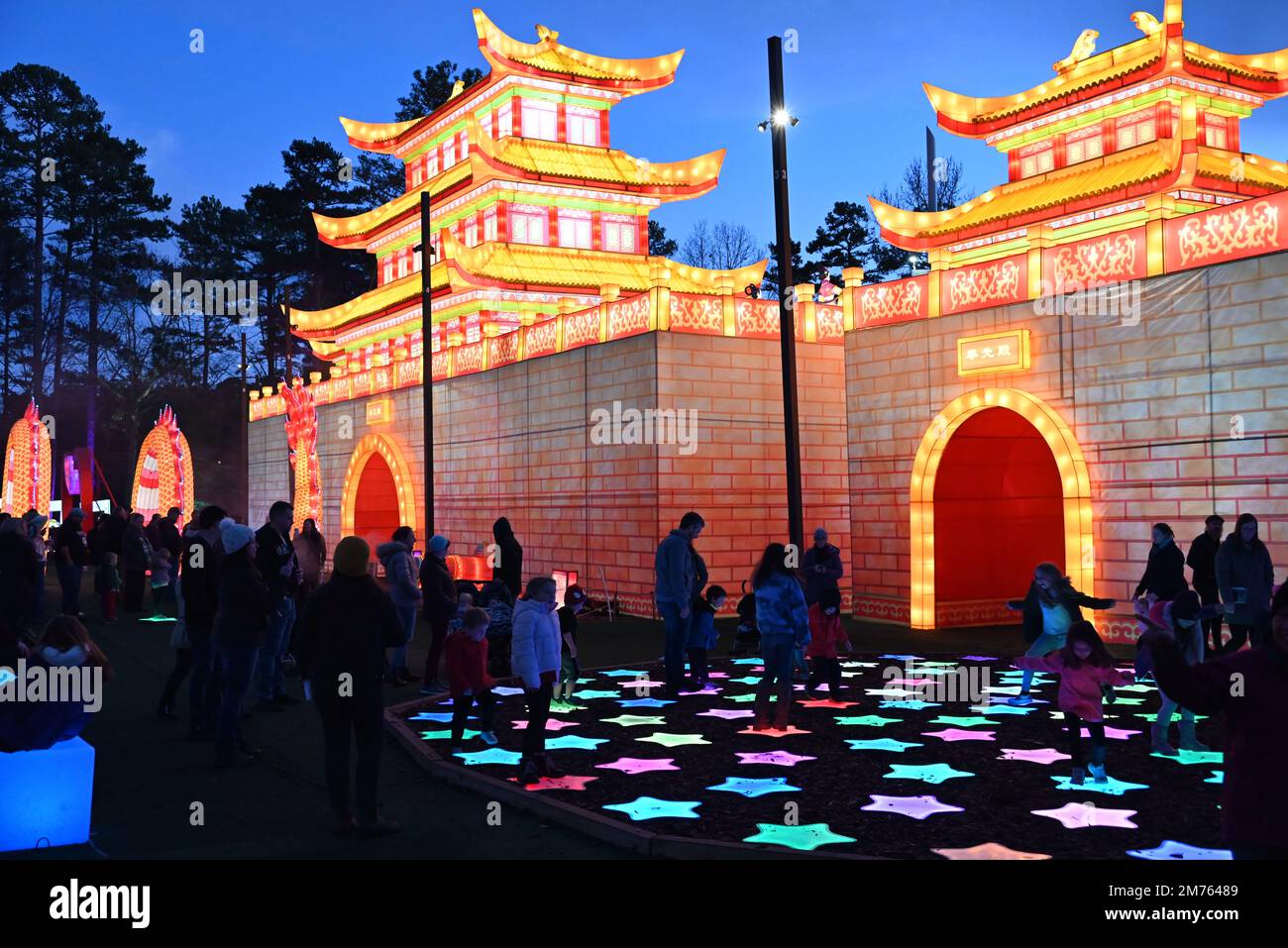 Children interact with lights outside the Dragon Palace as darkness