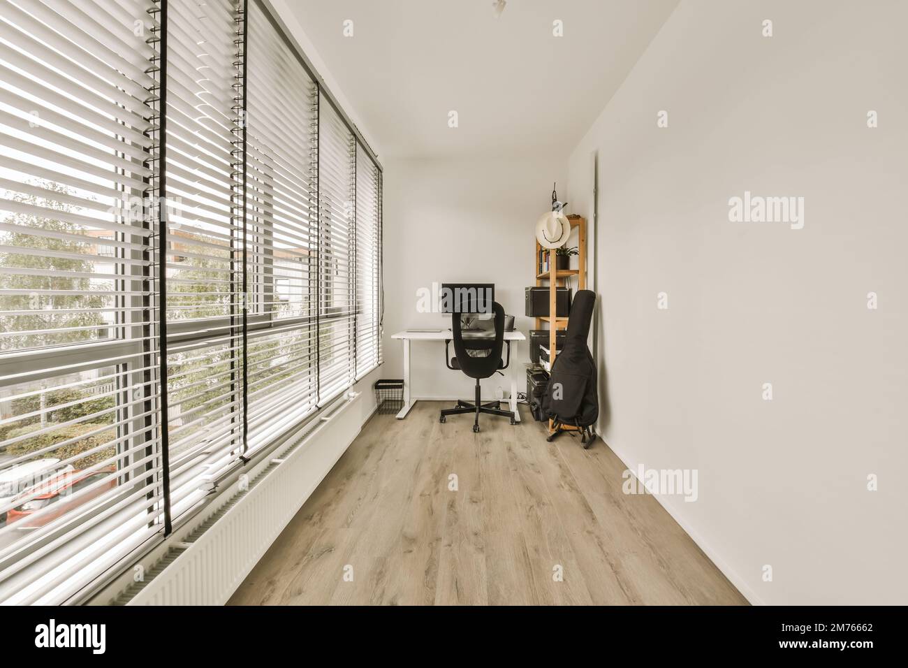 a home office with wood flooring and white shutters on the windows