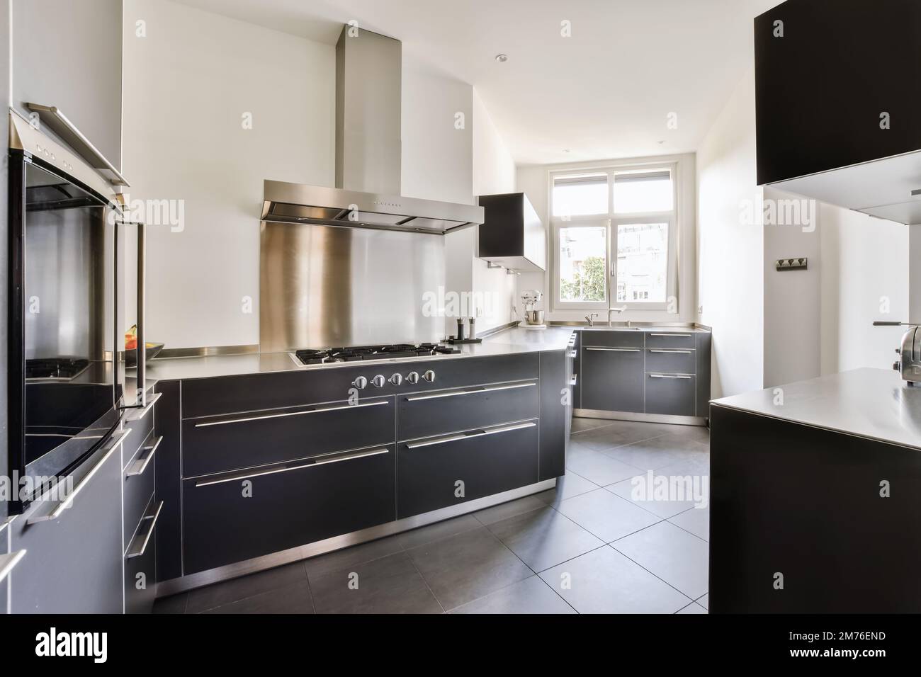 View of a modern kitchen with black cabinets and stainless steel appliances on ...