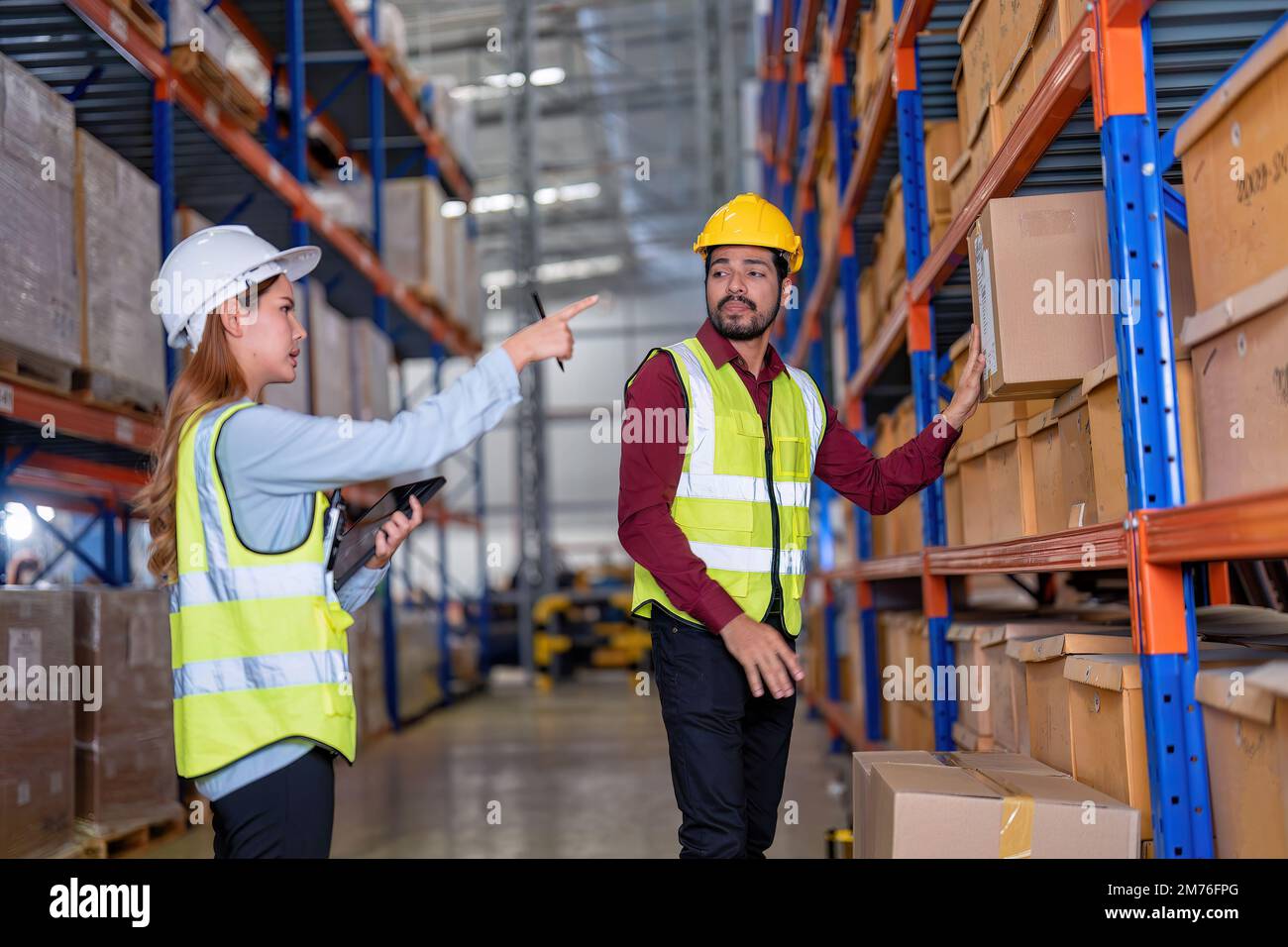 Warehouse worker hold the carton box walk along the steel racking shelf