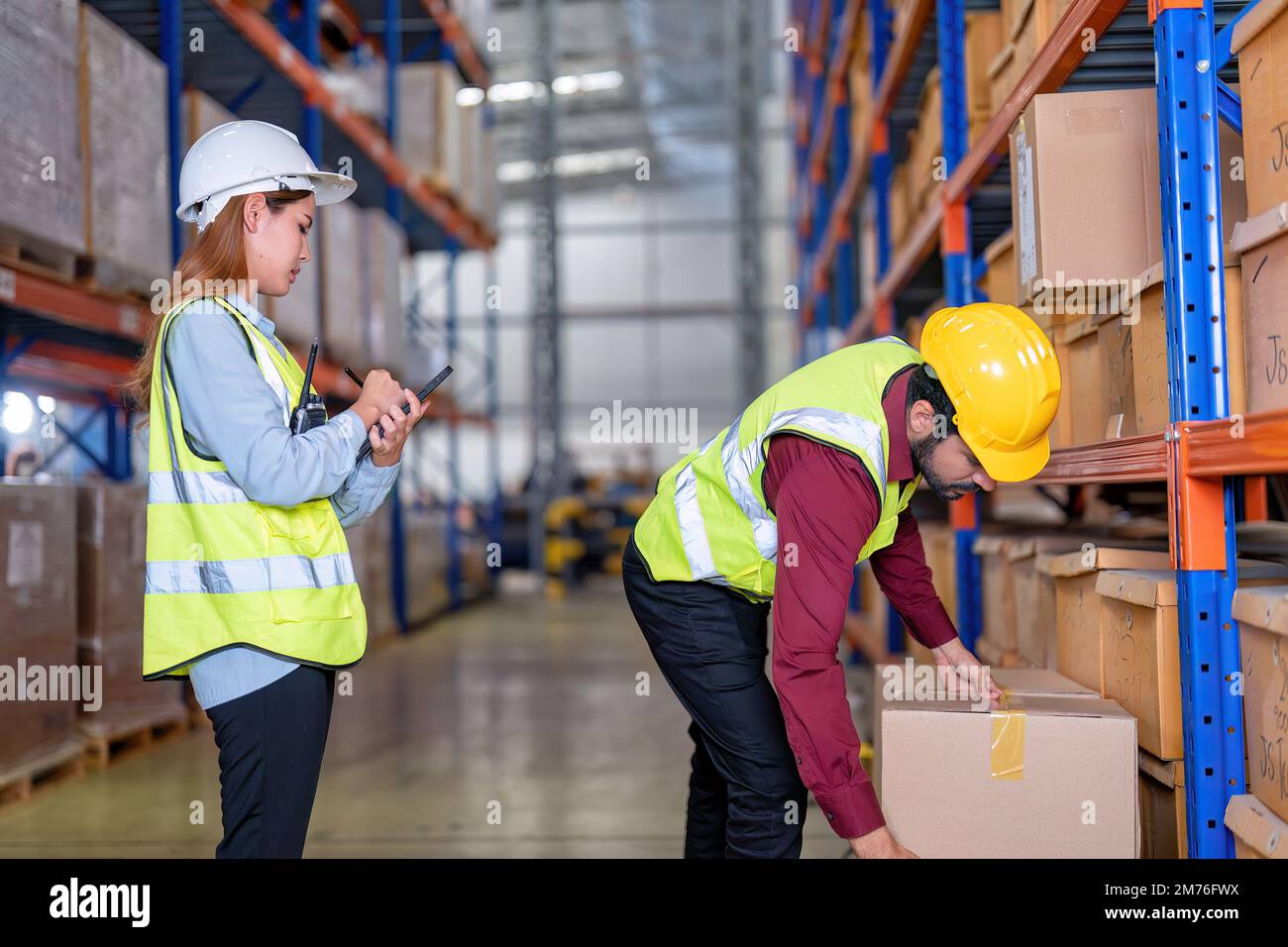 Warehouse worker hold the carton box walk along the steel racking shelf