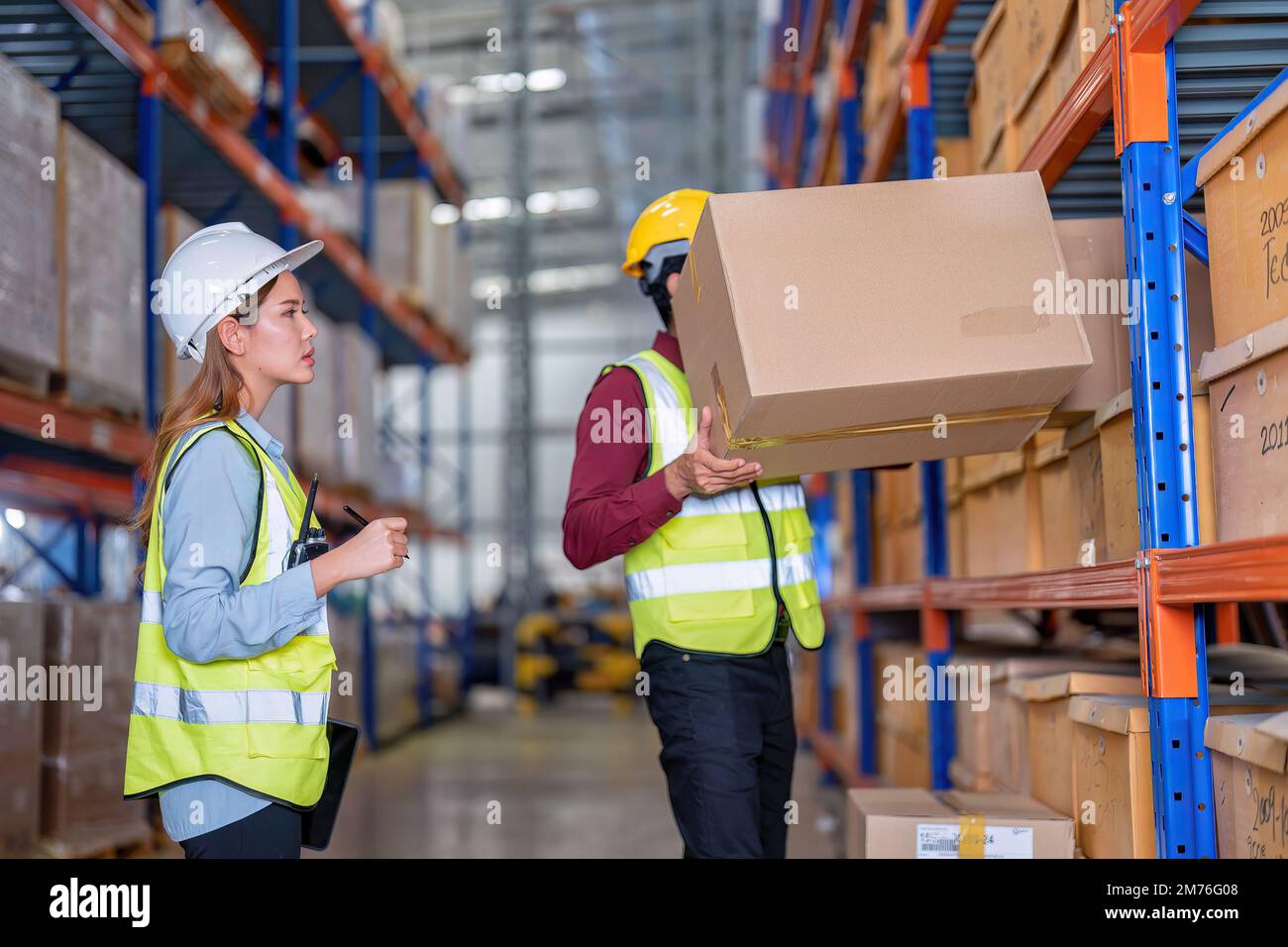 Warehouse worker hold the carton box walk along the steel racking shelf