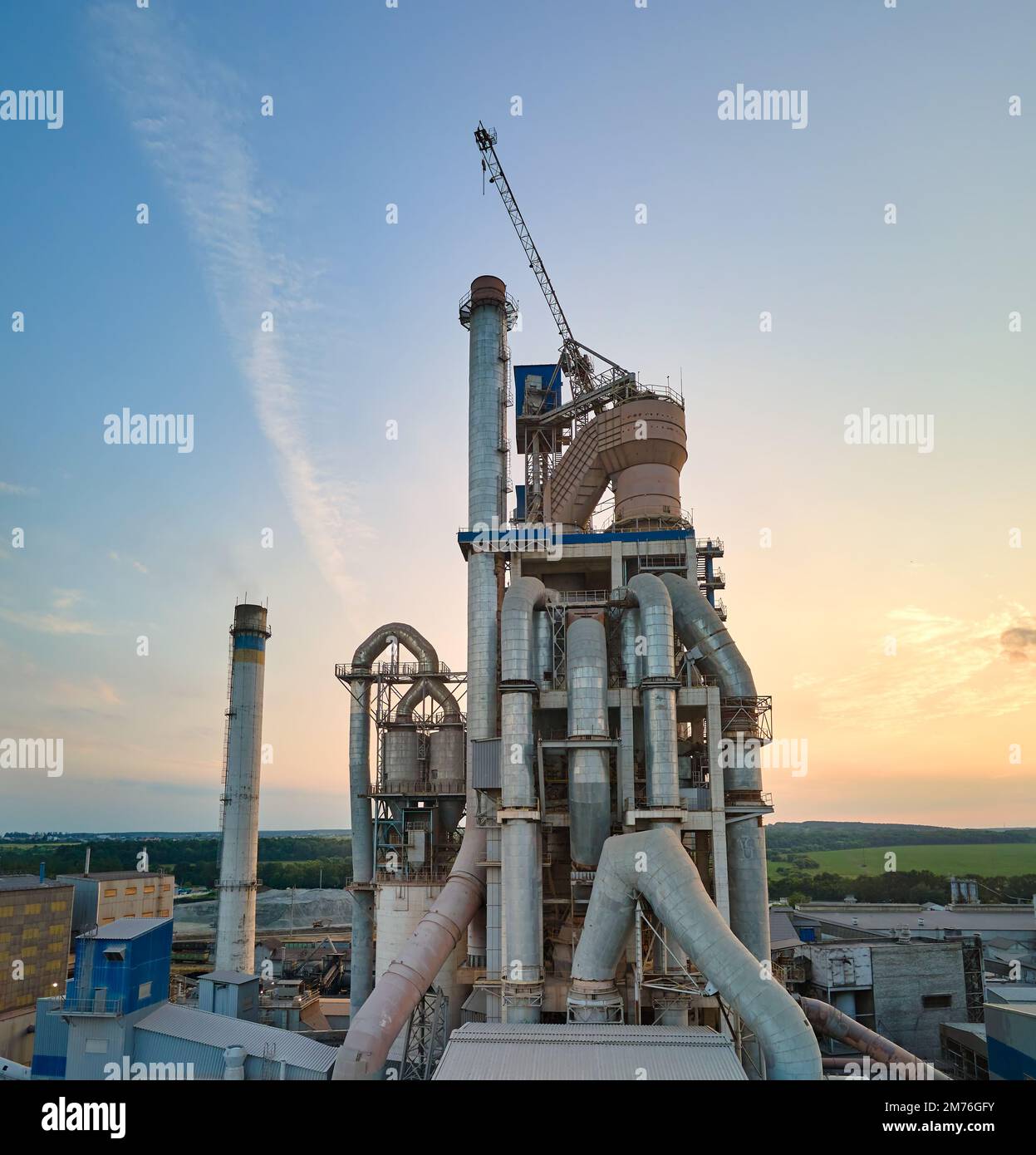 Cement plant with high factory structure and tower cranes at industrial production area. Manufacture and global industry concept Stock Photo