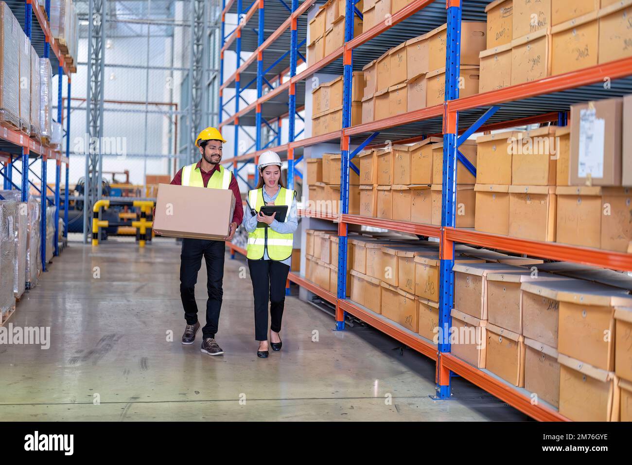 Warehouse worker hold the carton box walk along the steel racking shelf