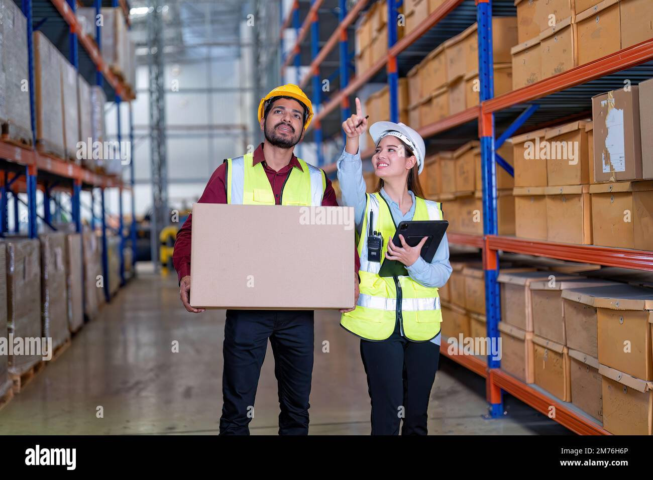 Warehouse worker hold the carton box walk along the steel racking shelf