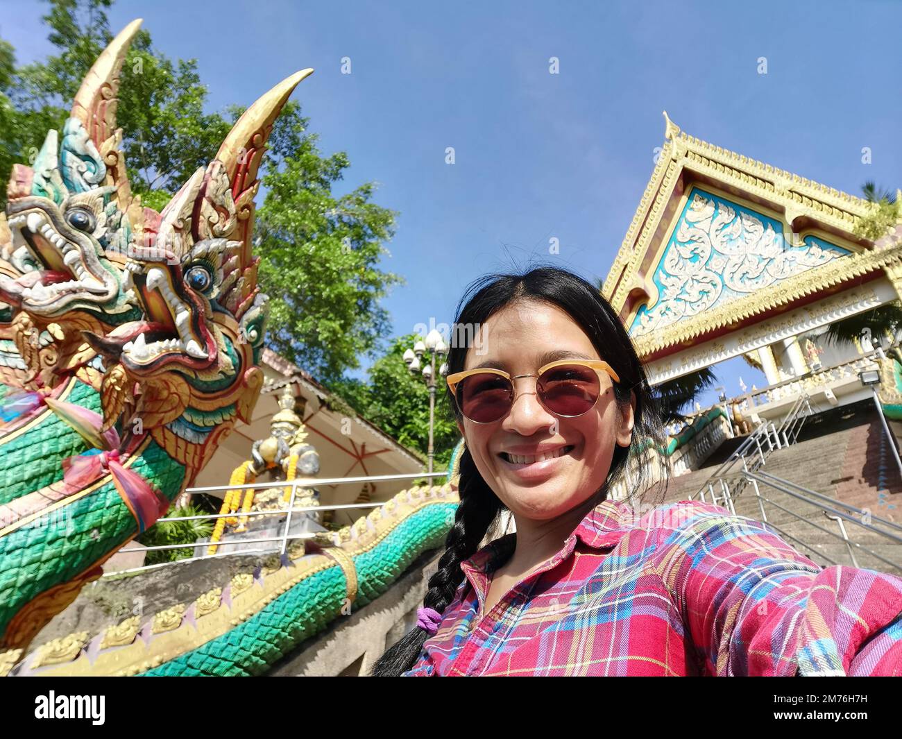A young tourtist taking selfie from the entrance to Wat Khao Rang a buddhist Thai temple on the island of Phuket, Thailand. Stock Photo