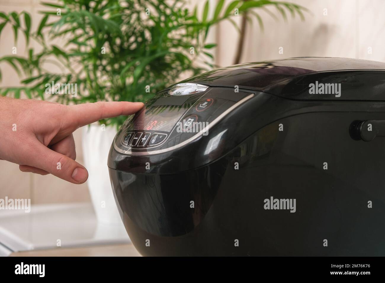Man closes lid of slow cooker and selects cooking program, temperature