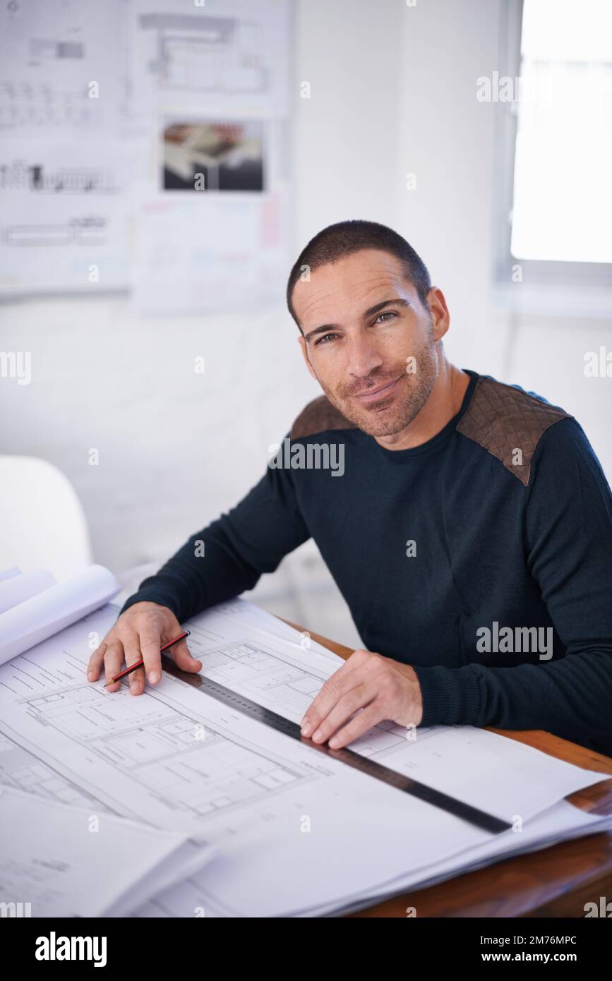 His ideas flow better in an uncluttered environment. Portrait of an architect drafting up building plans. Stock Photo