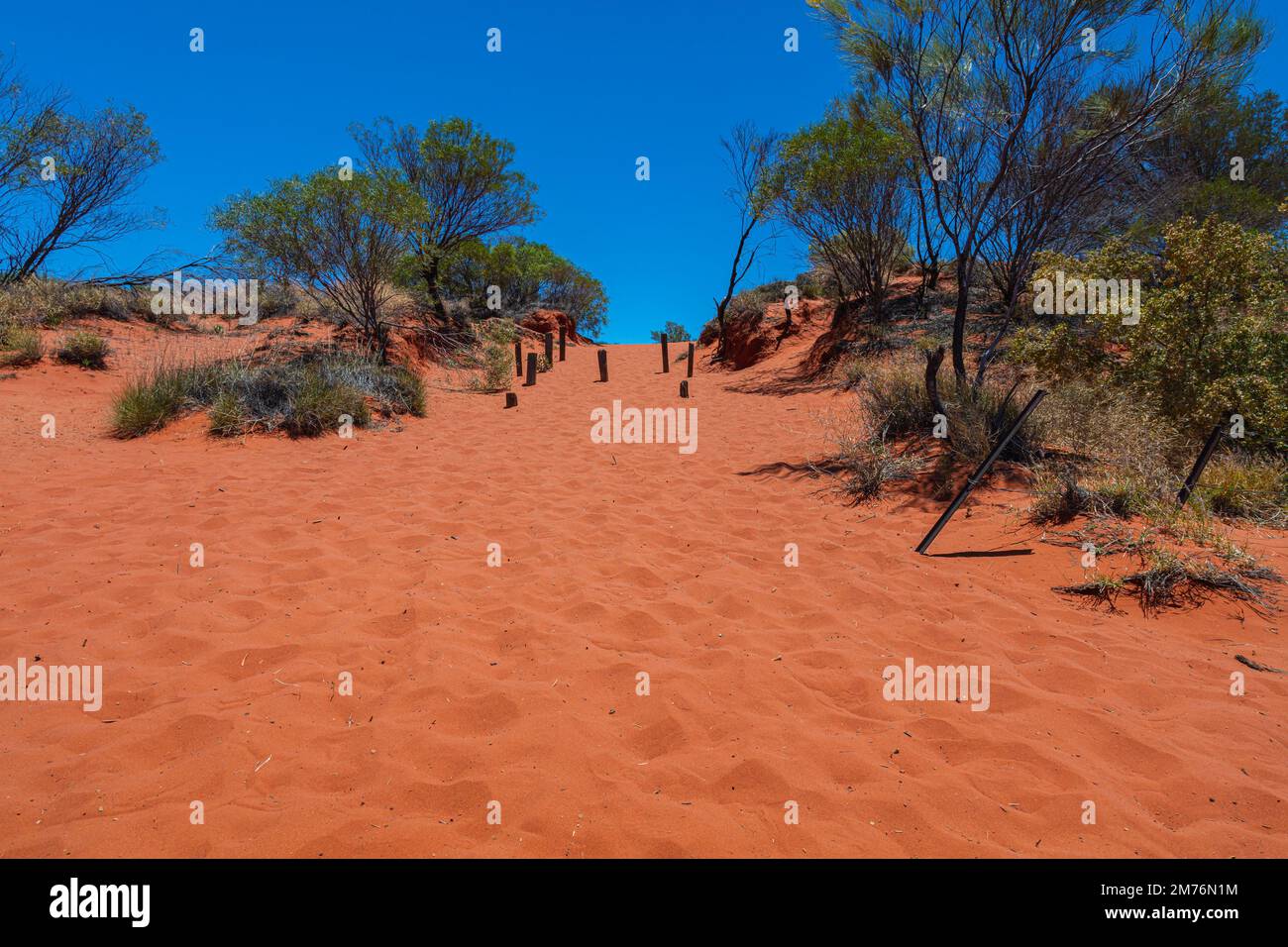 Sand dune beside the Stuart Highway. Behind the dune stretches a dry salt lake. Outback central Australia. Red sand and barren vegetation under blue s Stock Photo