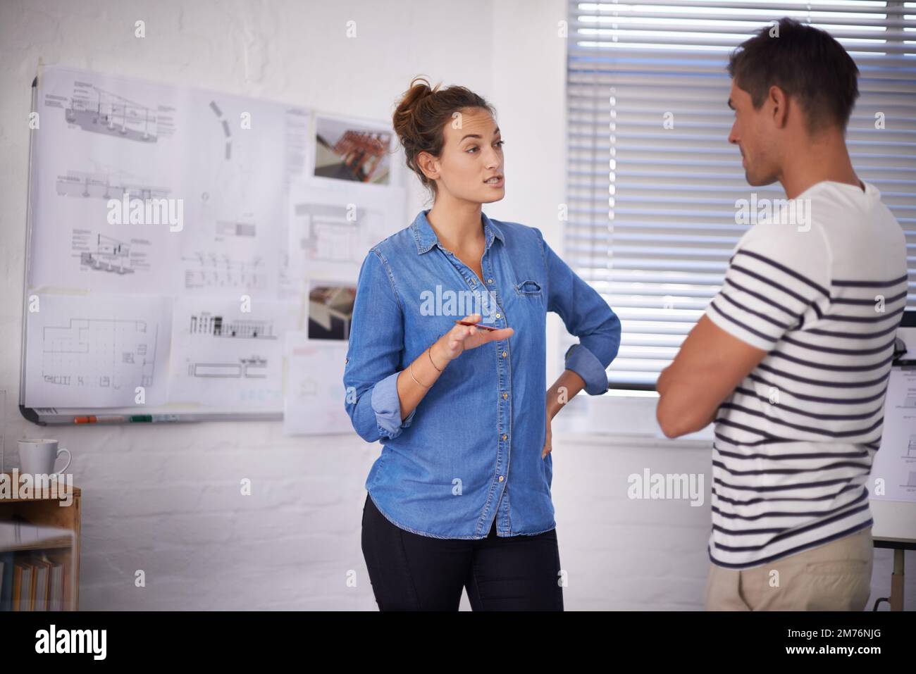 Discussing ideas for the blueprint. two young designers working together in an office. Stock Photo