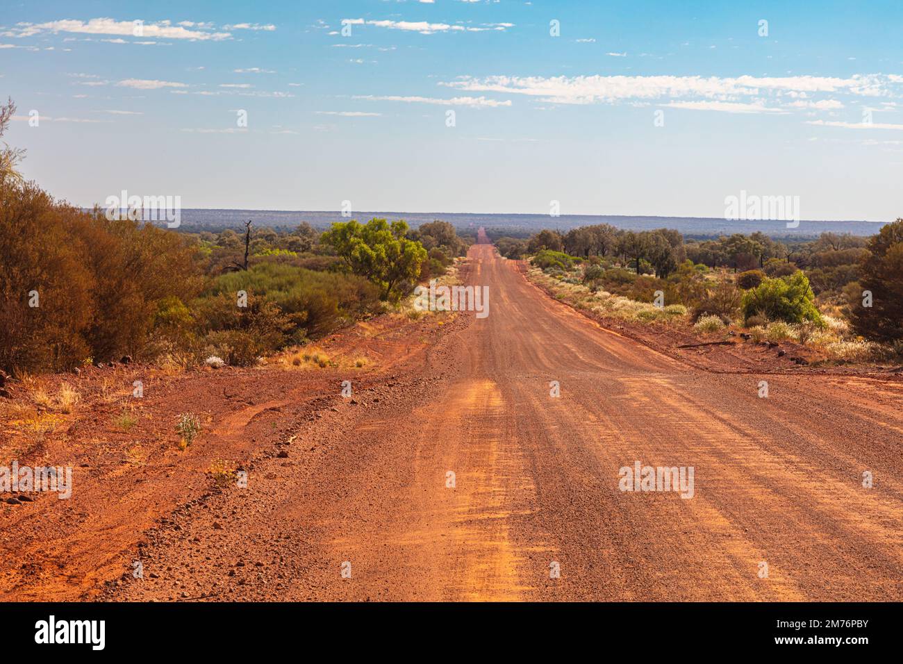 Unpaved road from Kings Canyon to Alice Springs near the Ginty's Lookout. Endless vast landscape with barren vegetation on thousands of kilometers in Stock Photo