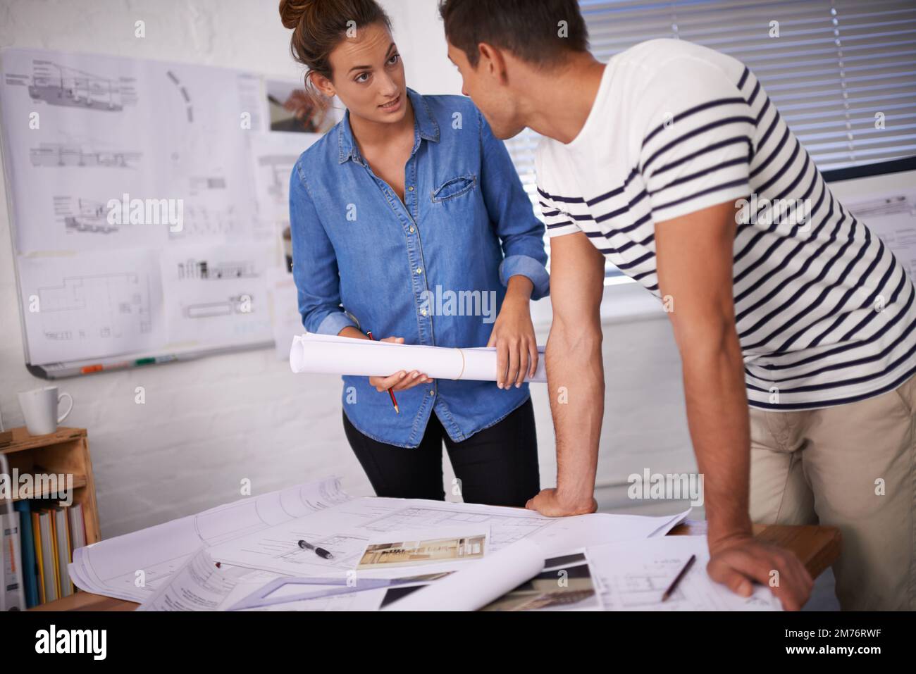 Working late to complete the blueprints. two young designers working together in an office. Stock Photo