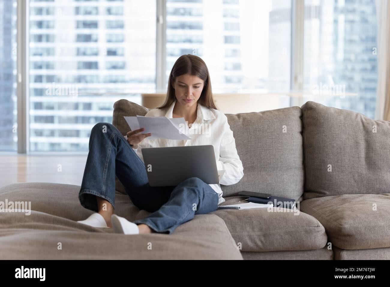 Busy woman sitting on sofa working or studying use laptop Stock Photo