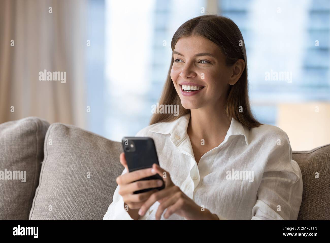 Attractive young woman resting on sofa with modern smartphone Stock Photo