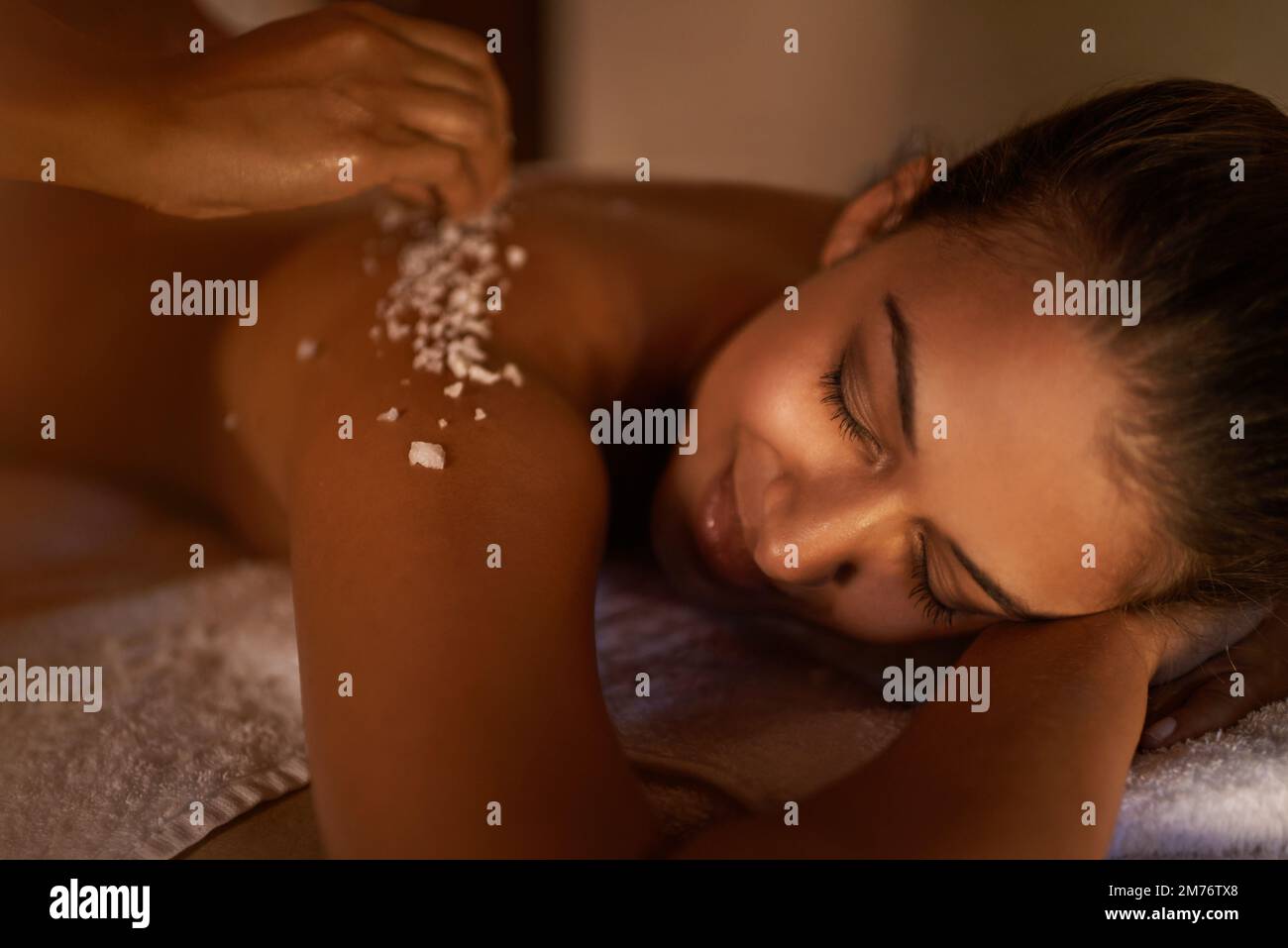 Keep calm and have a spa day. a young woman enjoying a salt exfoliation treatment at a spa. Stock Photo