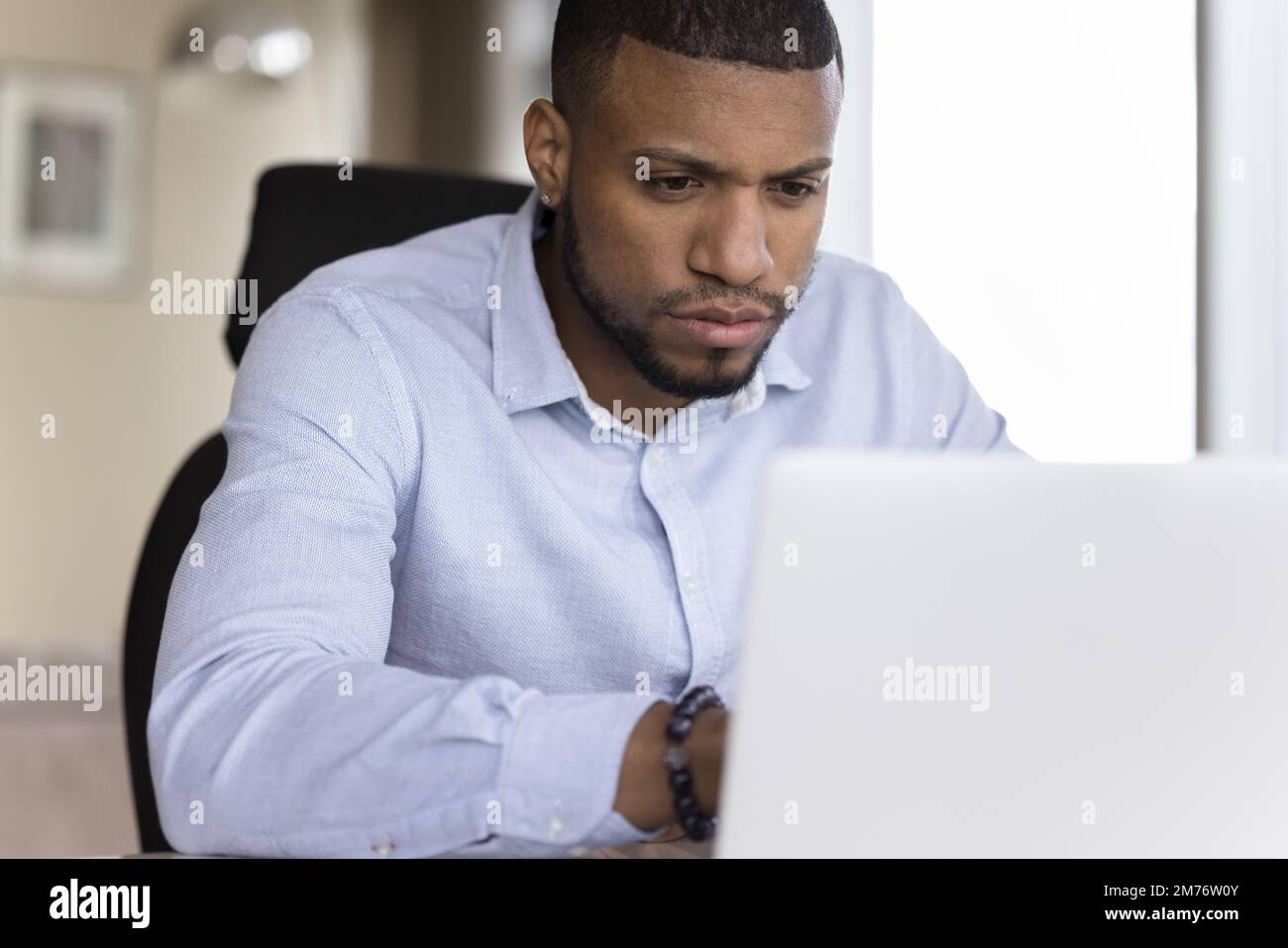 Focused African businessman working at workplace using laptop Stock Photo