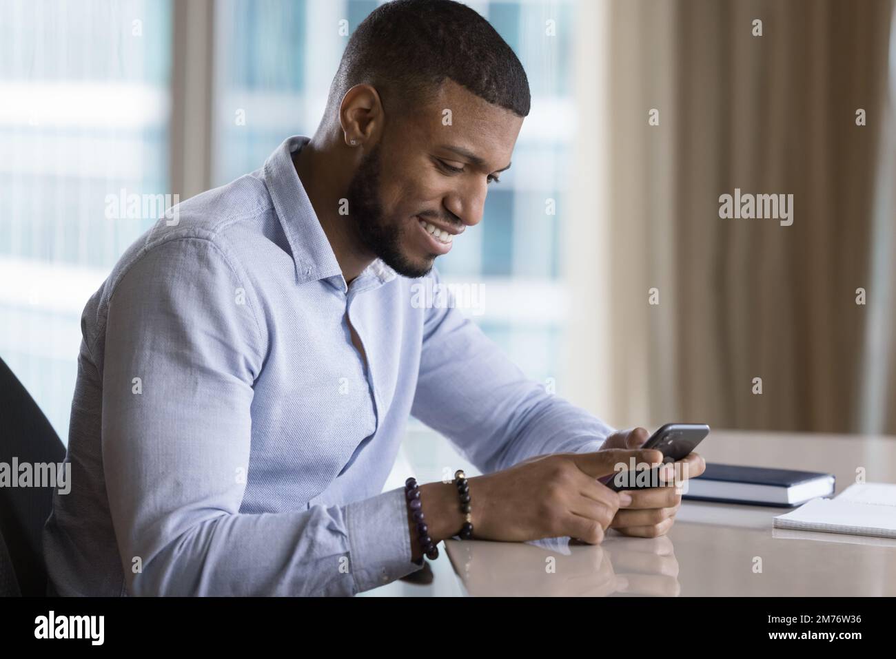 African business man holds cell phone at workplace Stock Photo