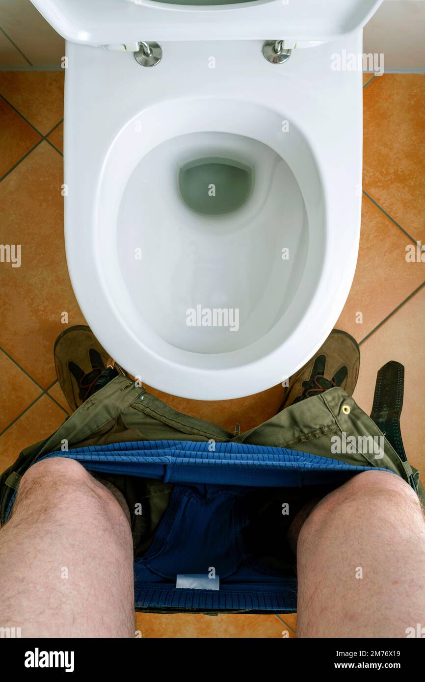 Mann steht vor einer Toilette, heruntergelassene Hosen Stock Photo