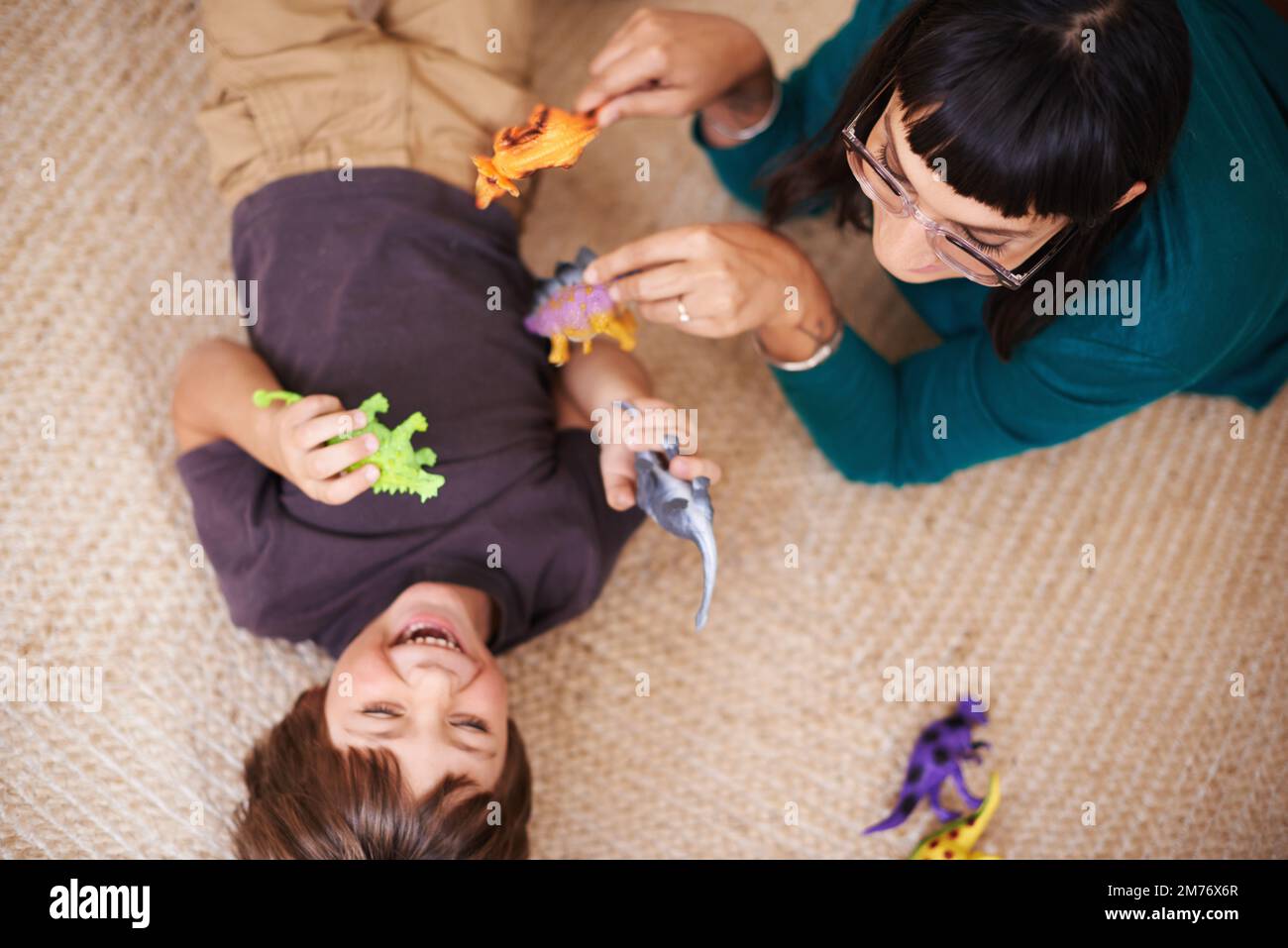 Watch out for the Ticklesaurus. a mother and her son playing with toy dinosaurs. Stock Photo