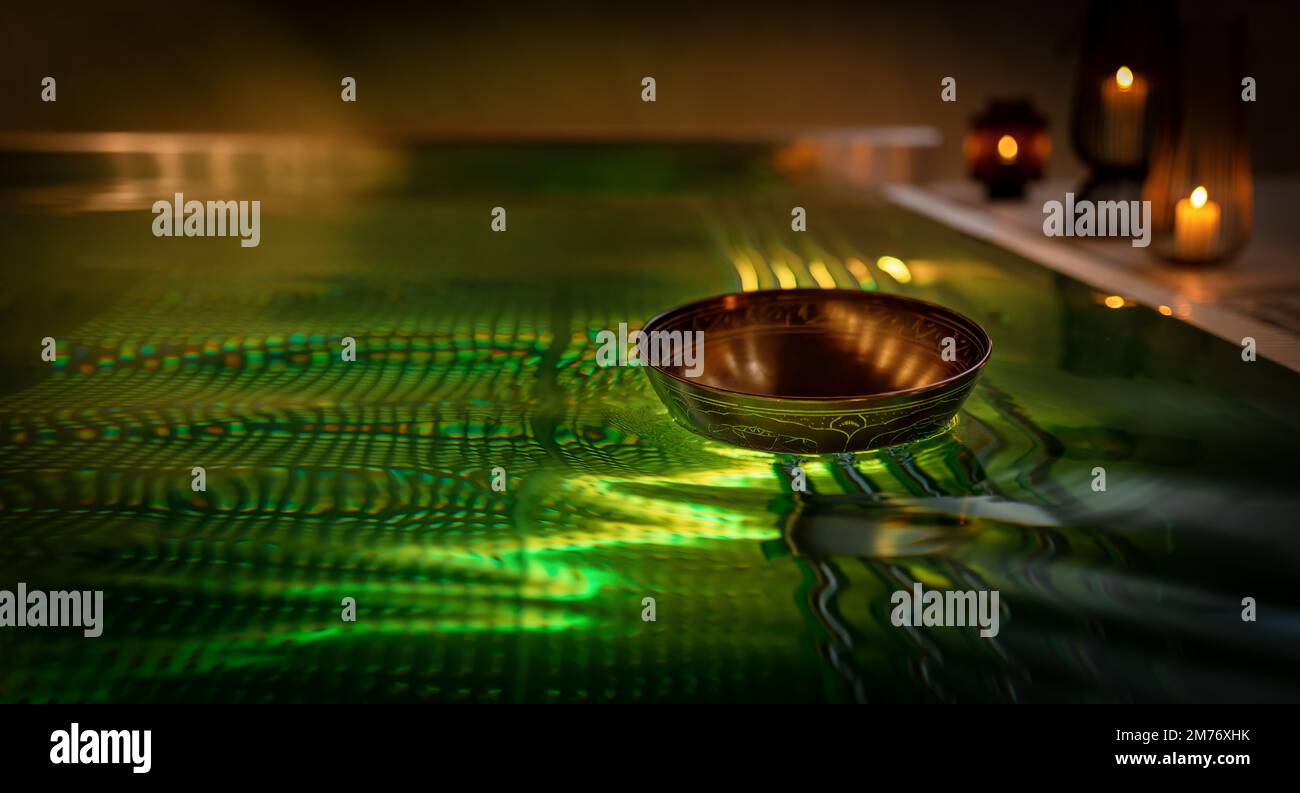 Tibetan bowl on the surface of the pool. Water relaxation and deep meditation. Stock Photo