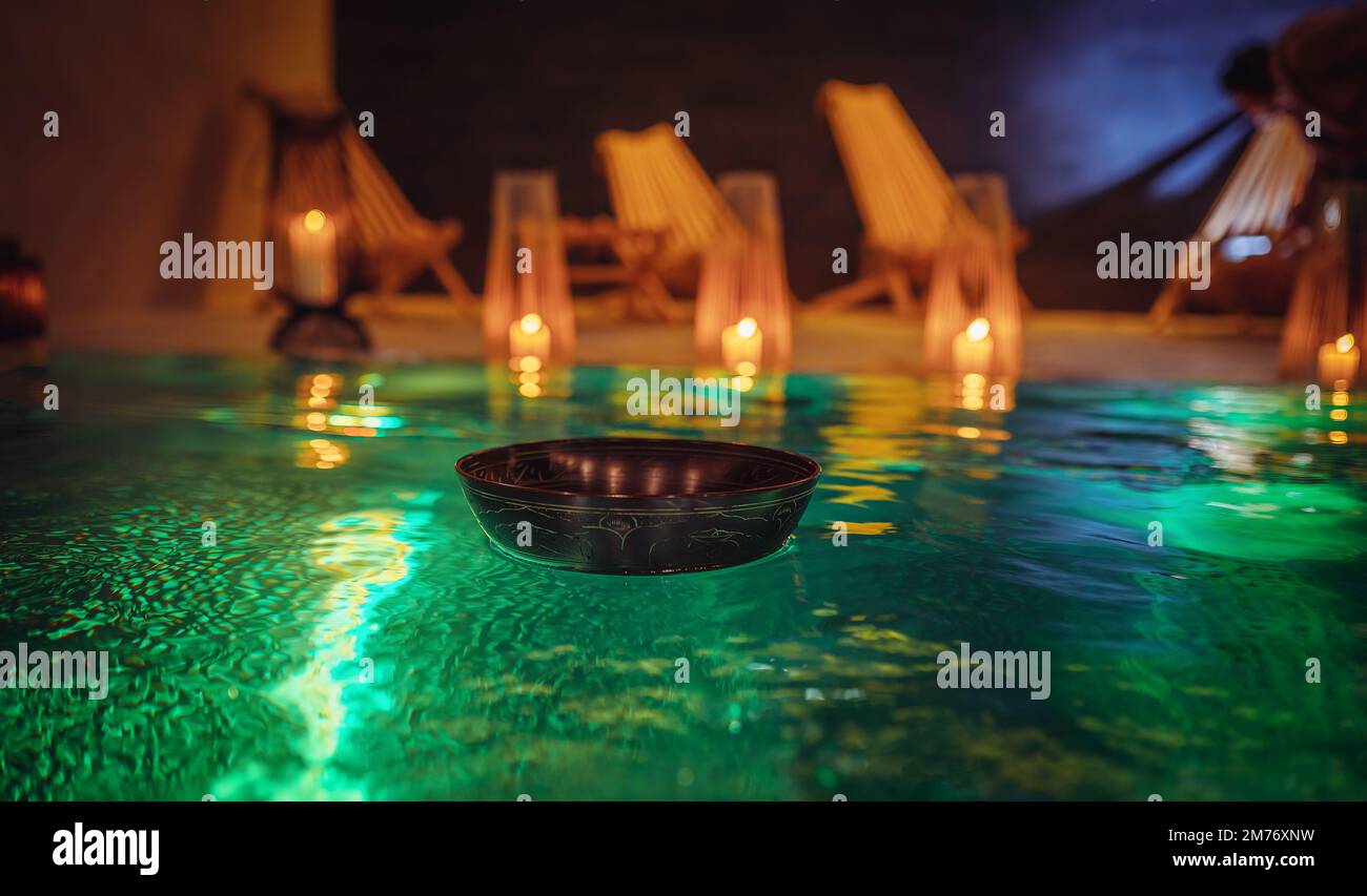 Tibetan bowl on the surface of the pool. Water relaxation and deep meditation. Stock Photo