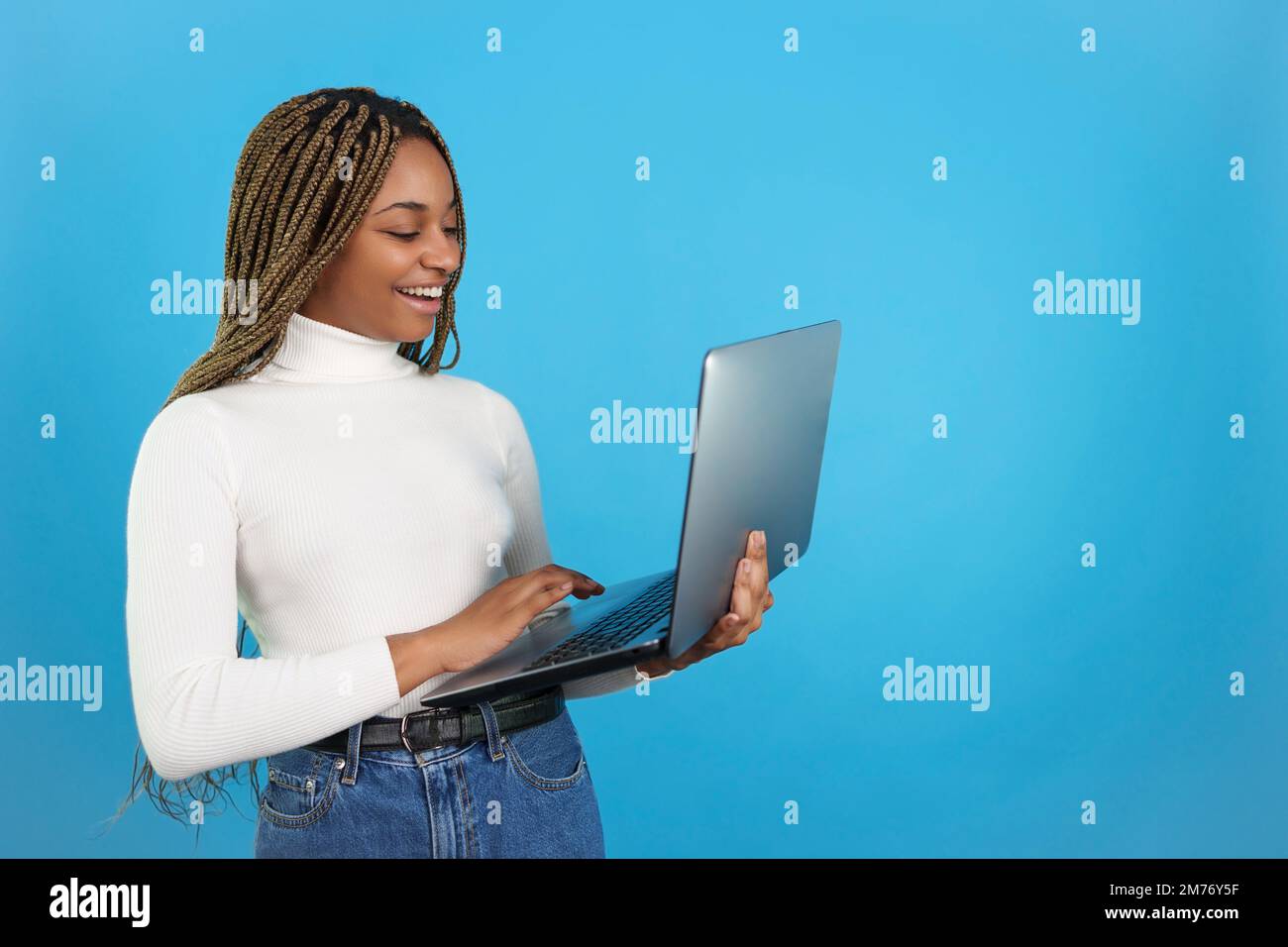 Happy african woman standing while using a laptop Stock Photo