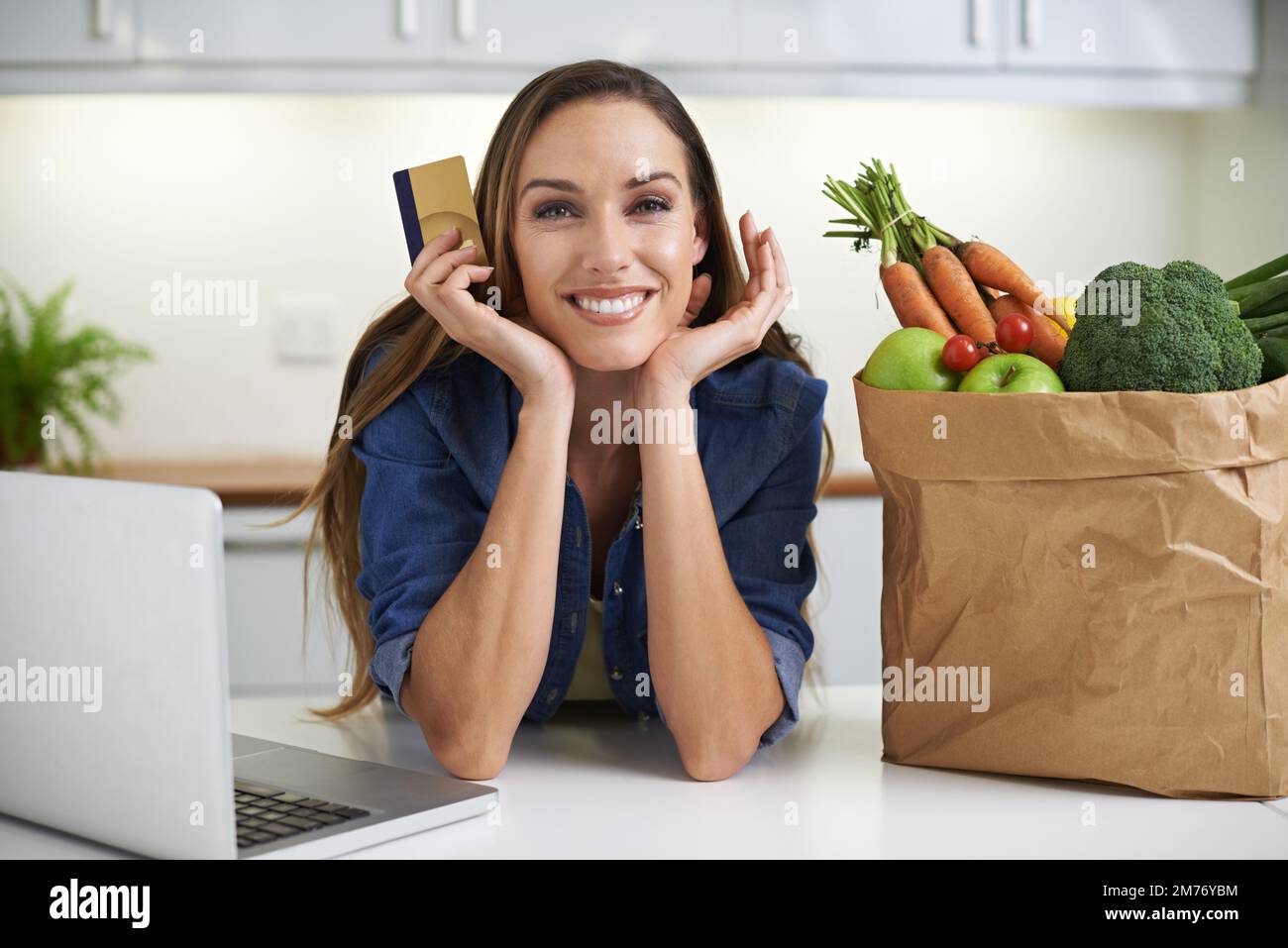Now that Ive got the groceries...online shopping. a young woman doing some online shopping with her groceries beside her. Stock Photo