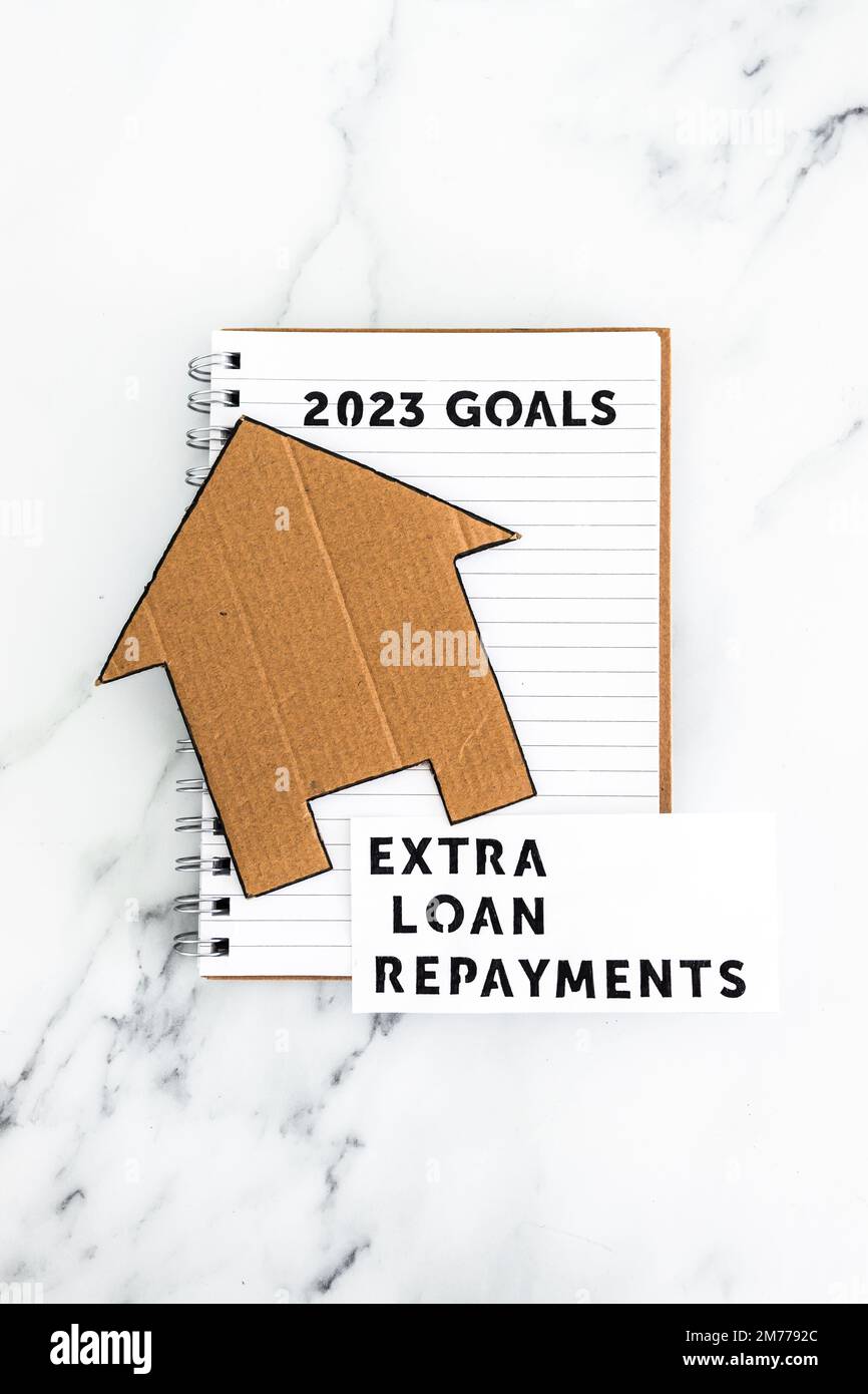 new year 2023 goals on notebook with cardboard house and extra loan payments text, concept of financial independence and being free from debt Stock Photo