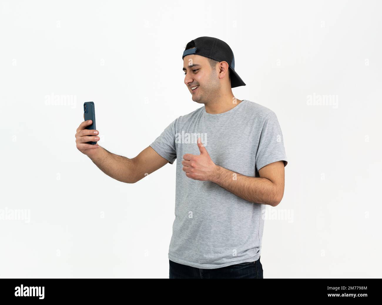 Close up photo of young boy wearing hat and using smartphone on isolated background. Stock Photo