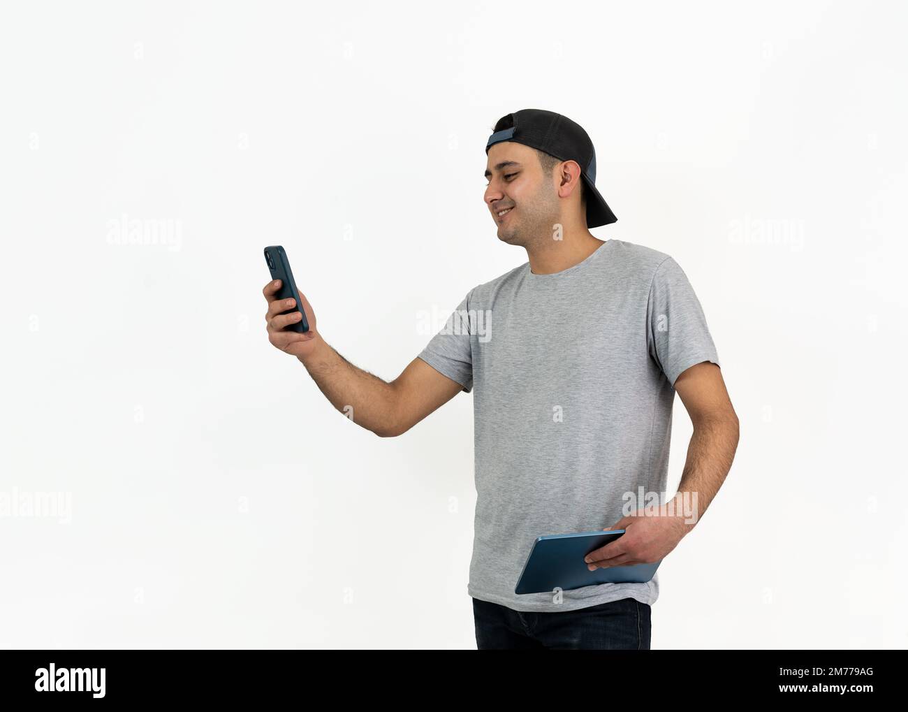 Close up photo of young boy wearing hat and using smartphone on isolated background. Stock Photo