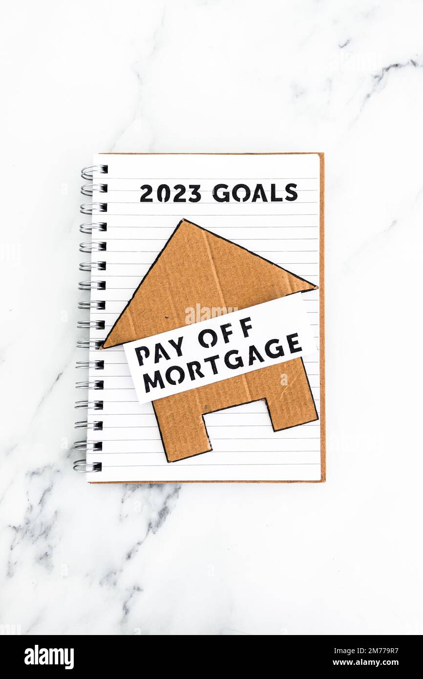 new year 2023 goals on notebook with cardboard house and Pay Off Mortgage text, concept of financial independence and being free from debt Stock Photo