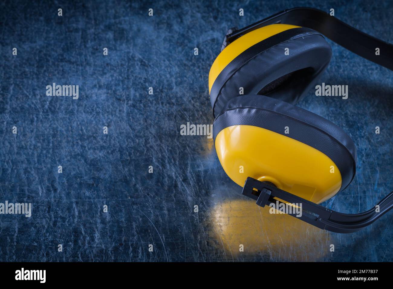 Noise reduction protective earmuffs on scratched metallic surface construction concept. Stock Photo