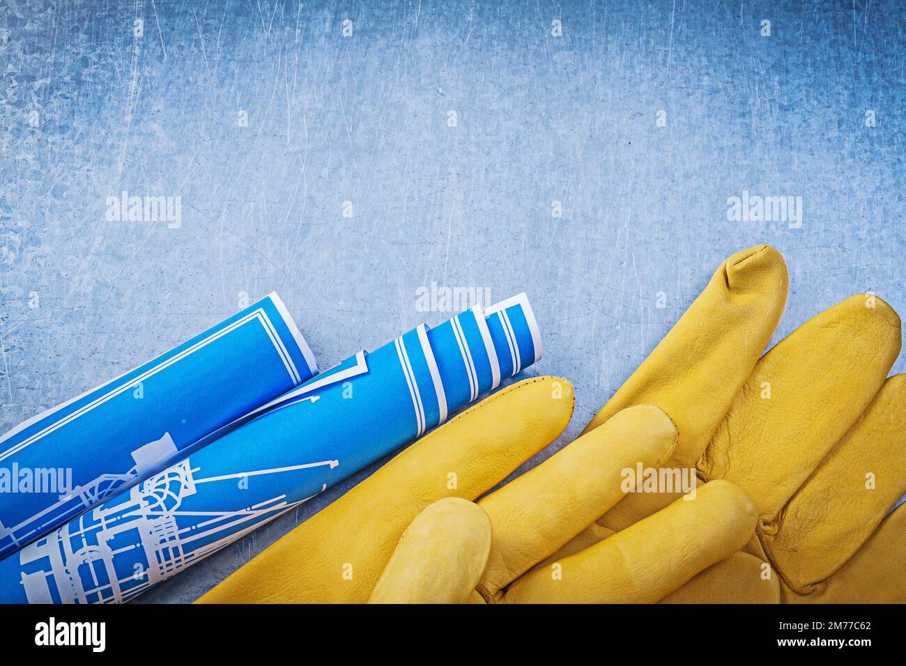 Pair of safety gloves blue rolled up construction plans Stock Photo - Alamy