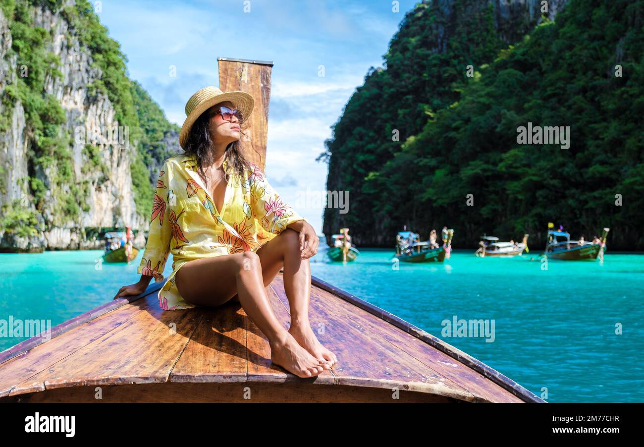Asian women in front of a longtail boat at Kho Phi Phi Thailand, women in front of a boat at Pileh Lagoon Stock Photo