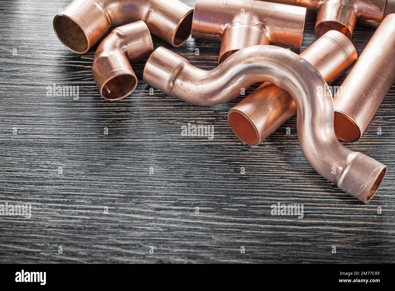 Plumbing copper water pipe fittings on wooden board. Stock Photo