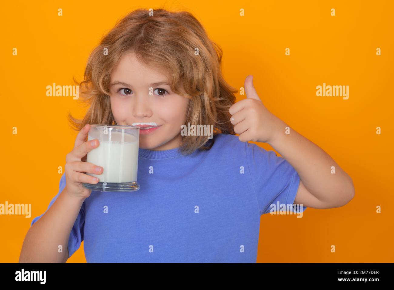 Dairy milk. Little child drinking milk. Kid with glass of milk on yellow isolated background. Stock Photo