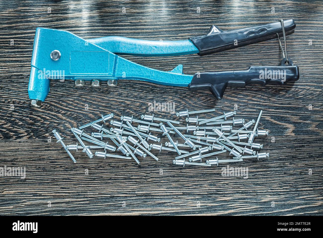 Riveting pliers screws on wooden board. Stock Photo