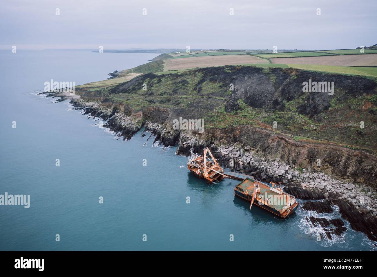 A drone view of the rusty ghost ships divided into two parts near the shore in Ballycotton, Ireland Stock Photo