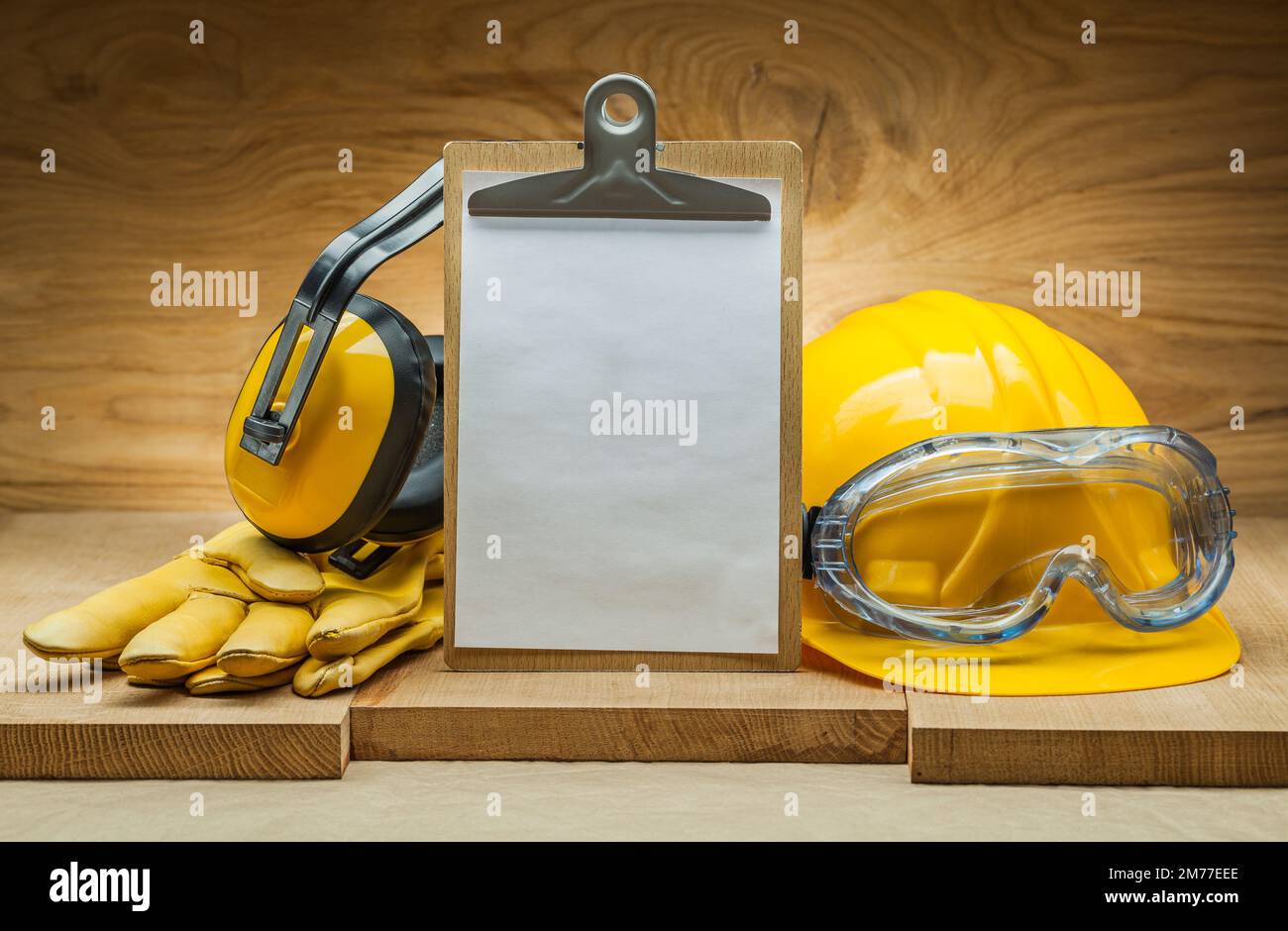 safety concept. blank sheet of paper for copyspace in clipboard. construction helmet and goggles yellow leather gloves earphones Stock Photo