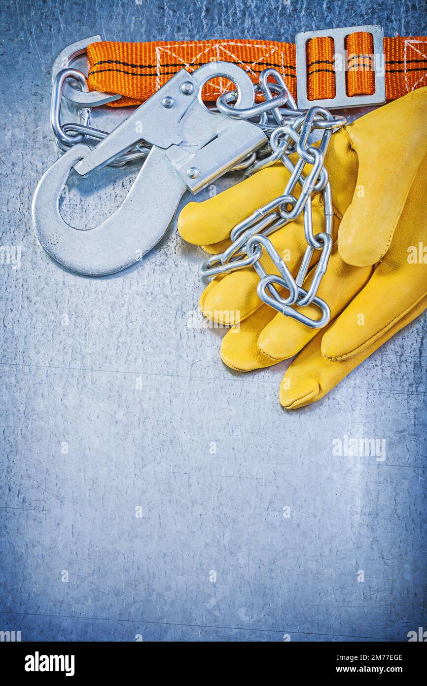 Safety construction body belt leather protective gloves on scratched metallic background. Stock Photo