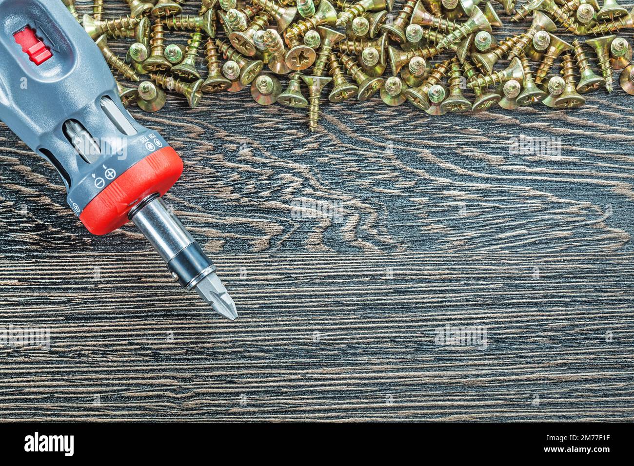 Screwdriver heap of screws on wooden board. Stock Photo