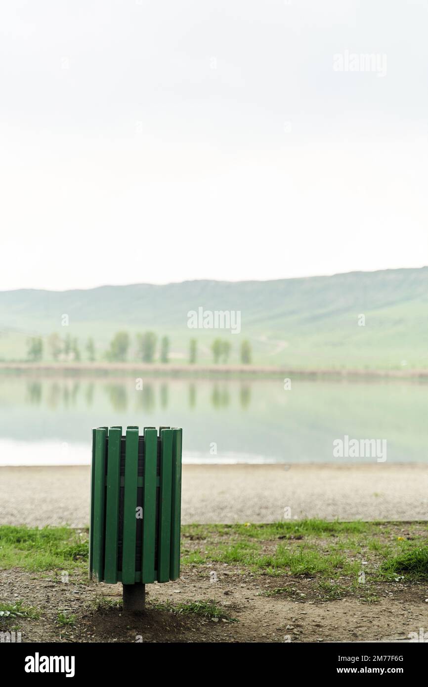 Green trash can on the shore of the lake Lisi Park in Tbilisi, Georgia Stock Photo