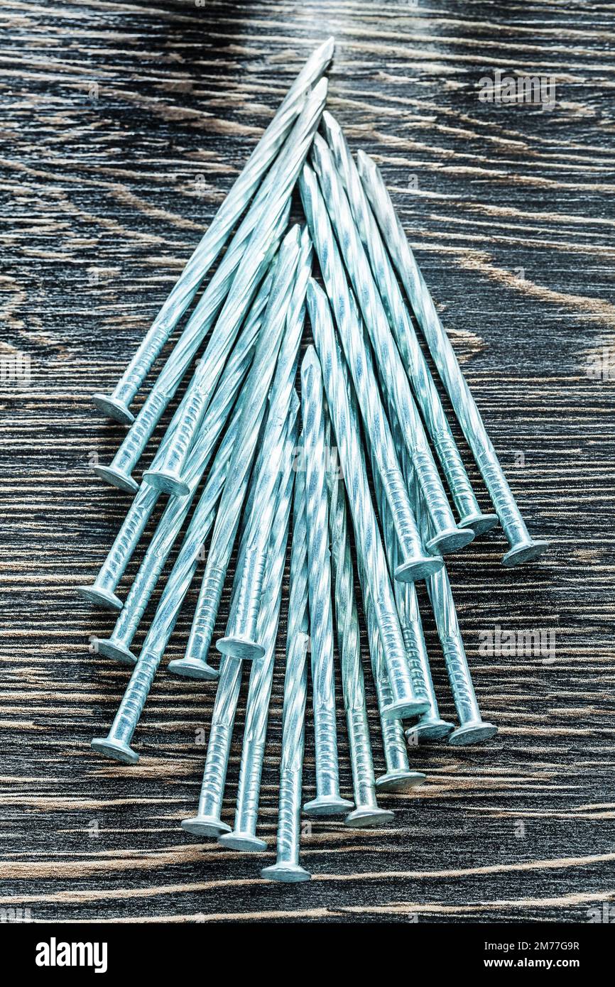 Stack of construction nails on wooden board. Stock Photo