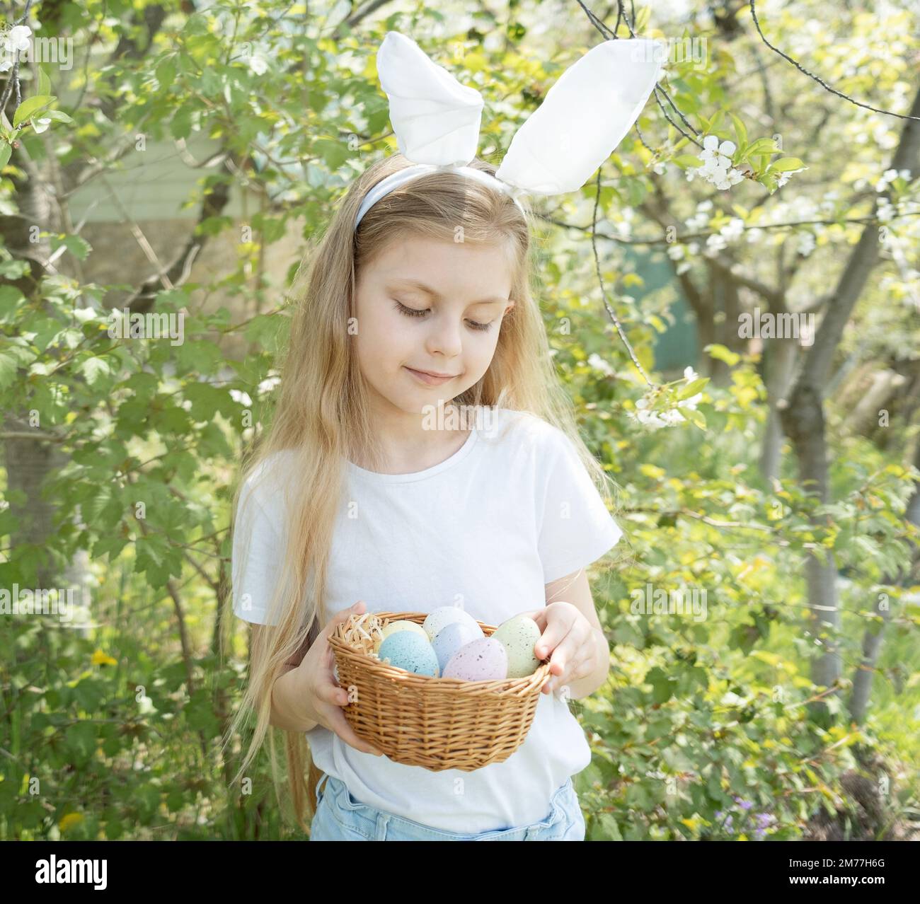 Cute little child wearing bunny ears on Easter day. Girl holding basket ...