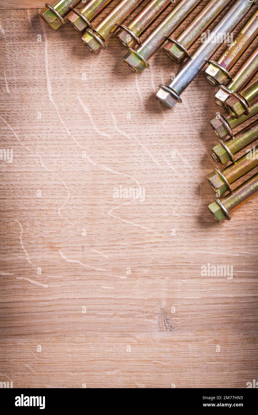 vertical version gold colored metalic anchors for concrete wall on wooden board with organized copyspace Stock Photo