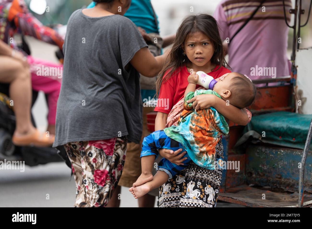 A young girl from the Badjao community holding a young baby in her arms.Philippines Stock Photo